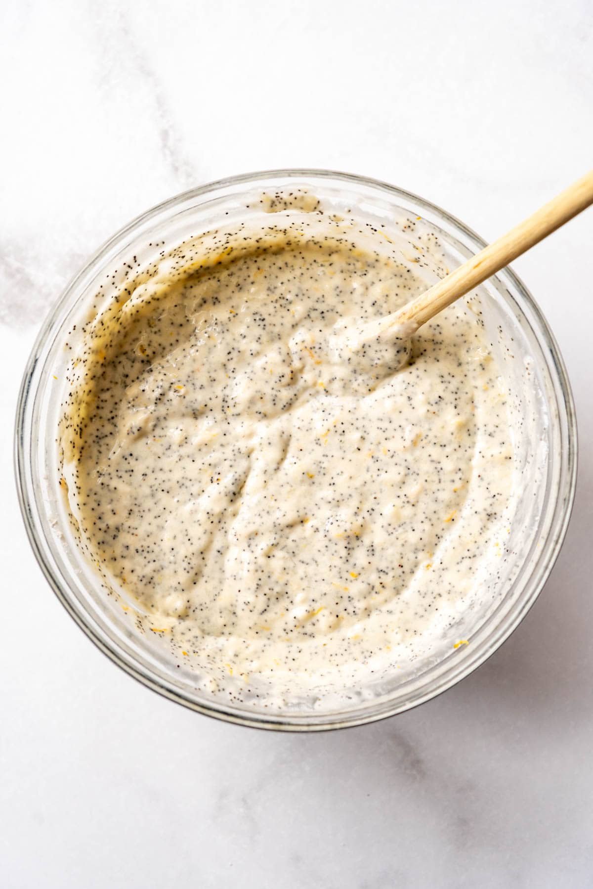 Lemon poppy seed pancake batter in a bowl with a wooden spoon.