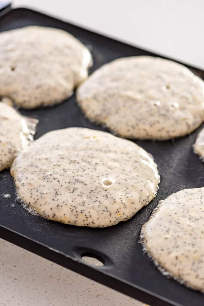 Pancakes cooking on a griddle.