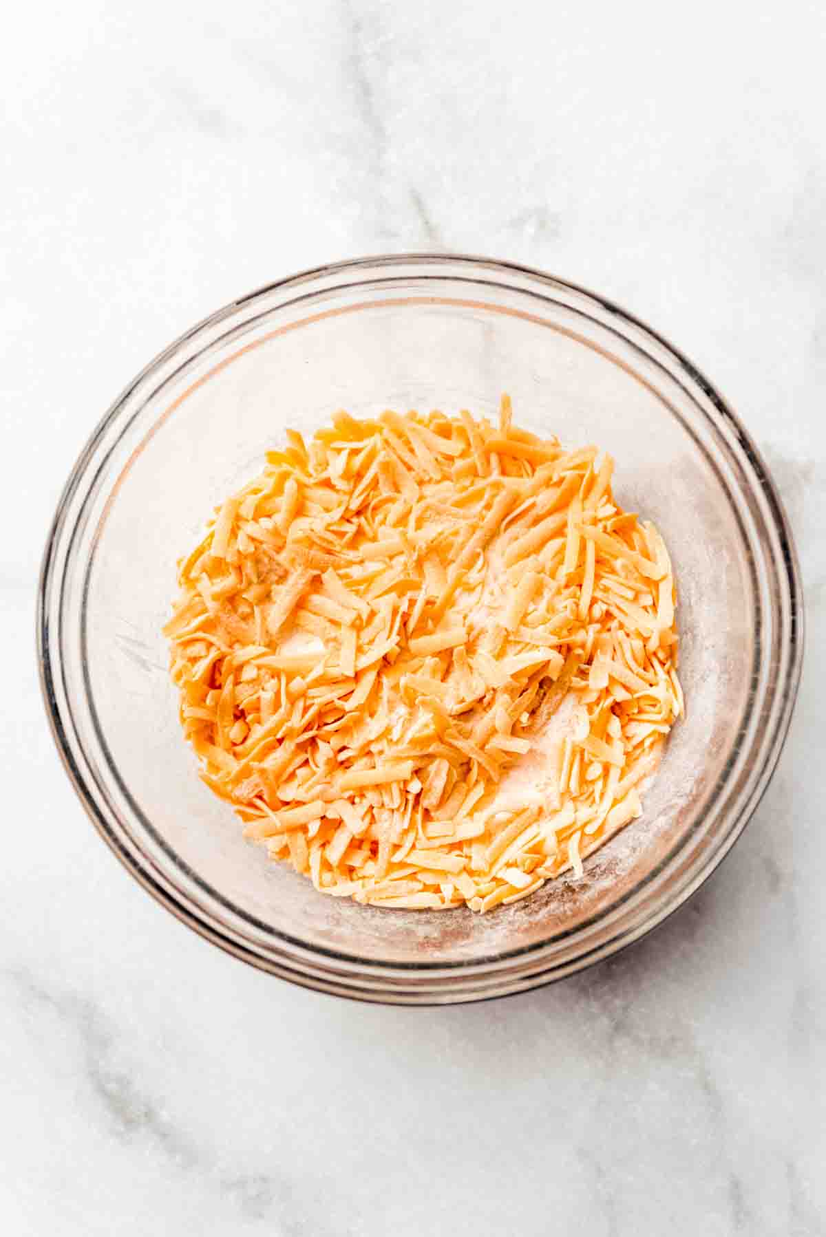 Pineapple casserole ingredients are combined in a clear glass mixing bowl. 