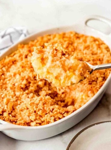 A serving spoon holding a scoop of pineapple casserole.