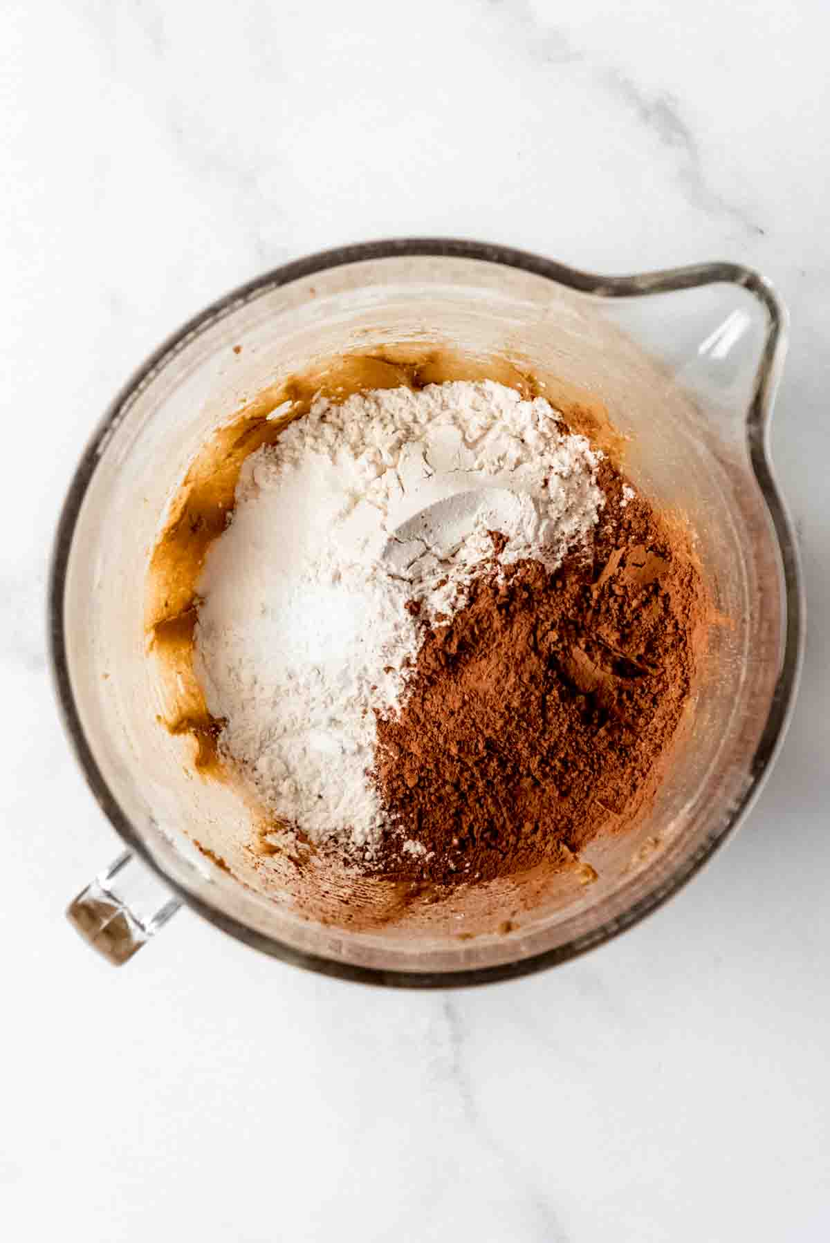 Dry ingredients are added to a clear mixing bowl. 