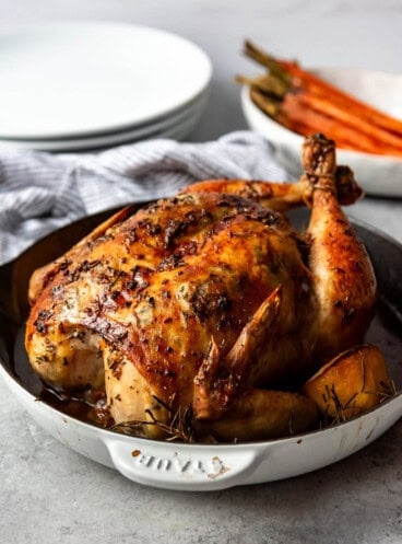 A whole roasted chicken in shallow dutch oven.