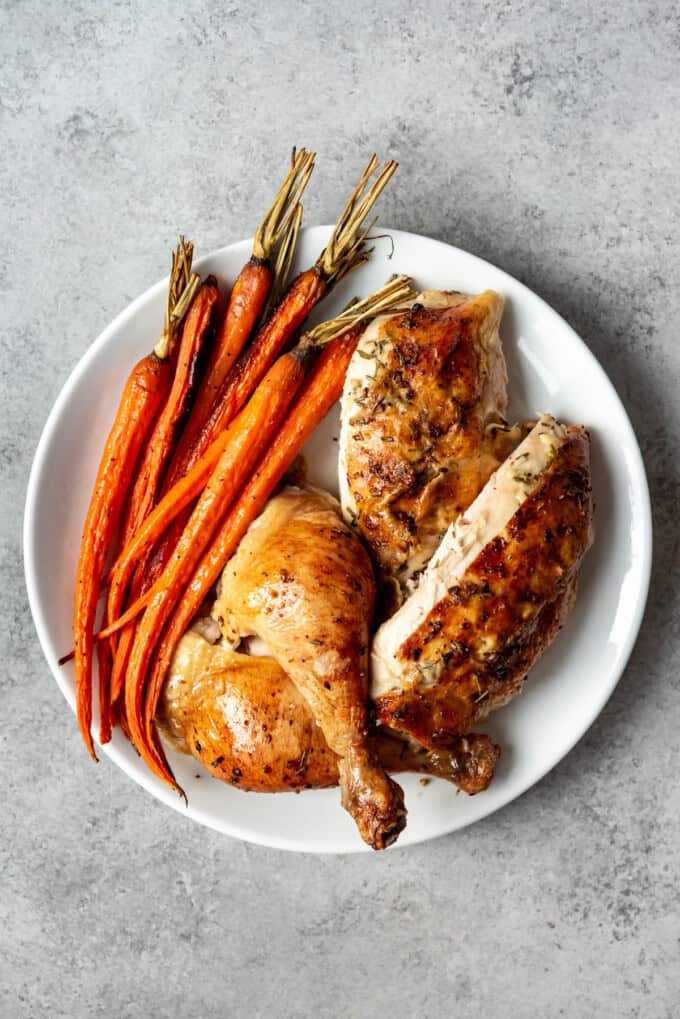 An image of a plate of roast chicken and roast carrots.