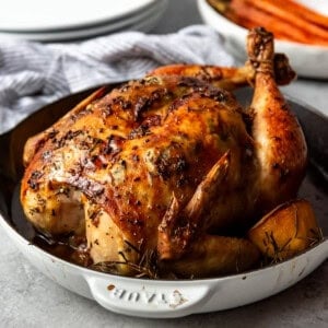 A whole roasted chicken in shallow dutch oven.