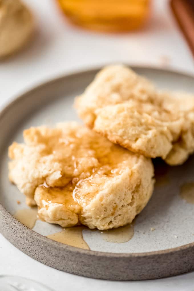 Close up of drop biscuits on a grey plate covered in honey.