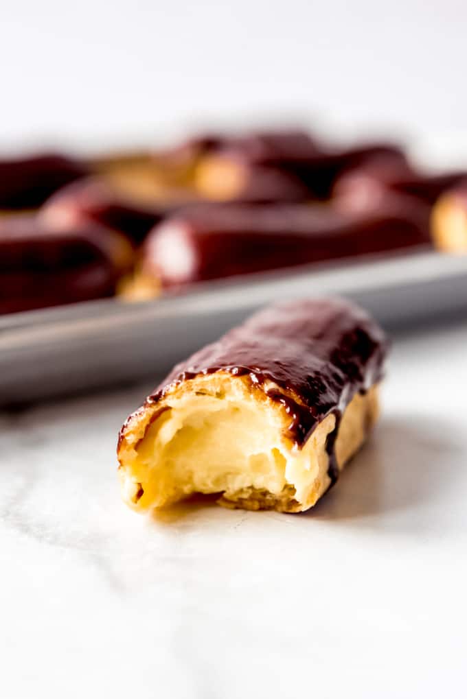 a pastry cream filled chocolate eclair with a bite taken out of it