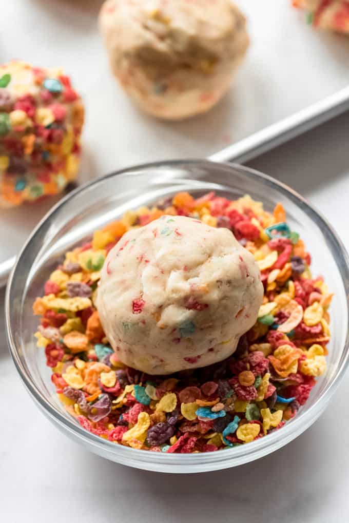 Rolling a ball of cookie dough in Fruity Pebbles cereal.