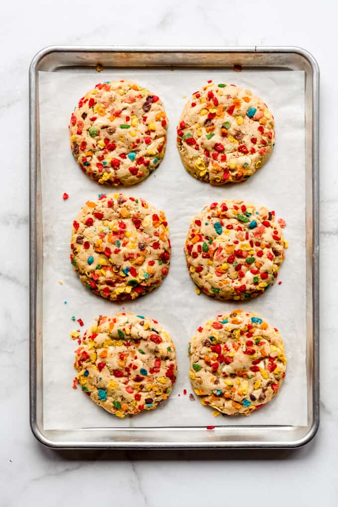 Baked Fruity Pebbles cookies on a baking sheet lined with parchment paper.
