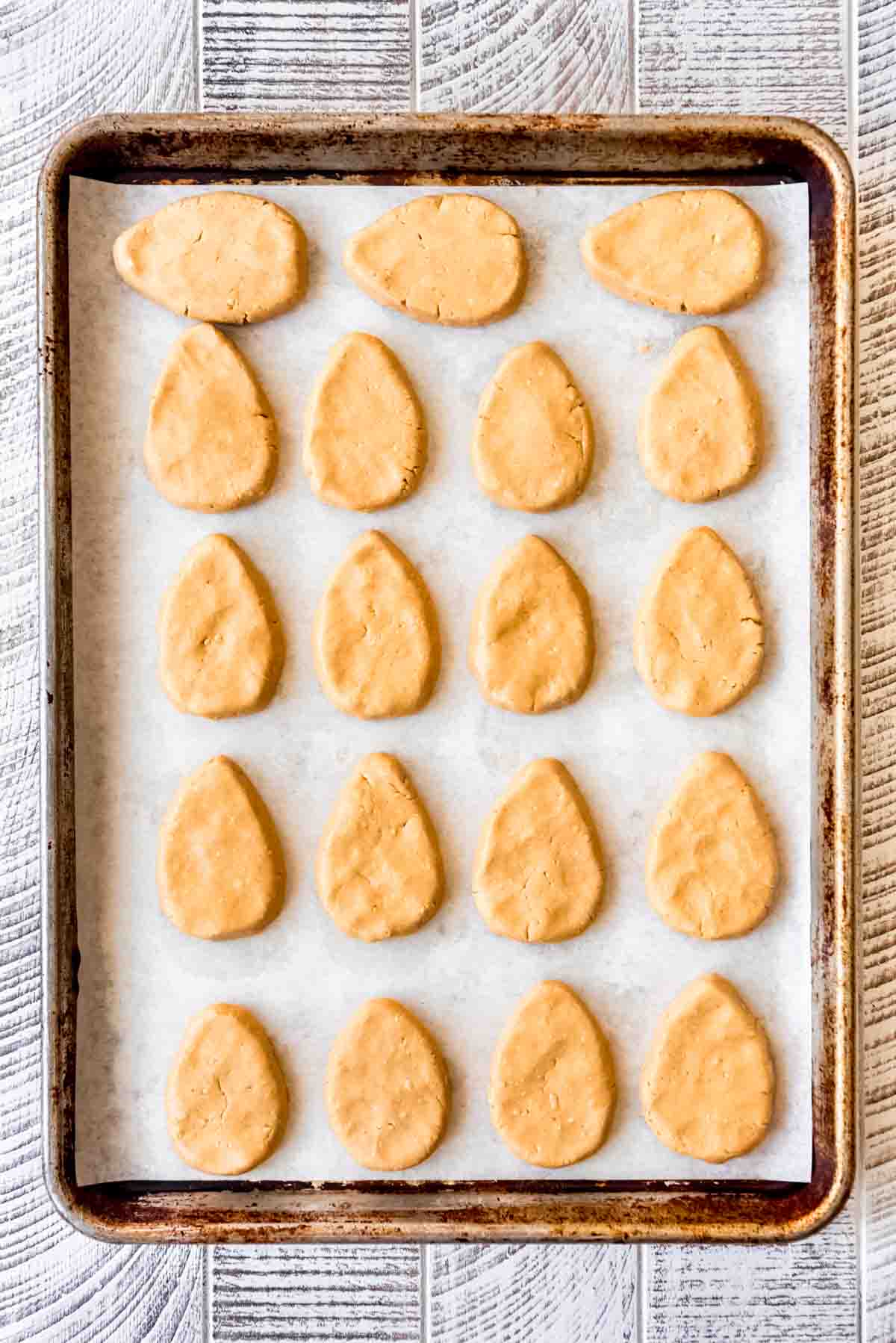 Peanut butter mixture has been shaped into egg shapes, resting on a parchment lined baking sheet. 