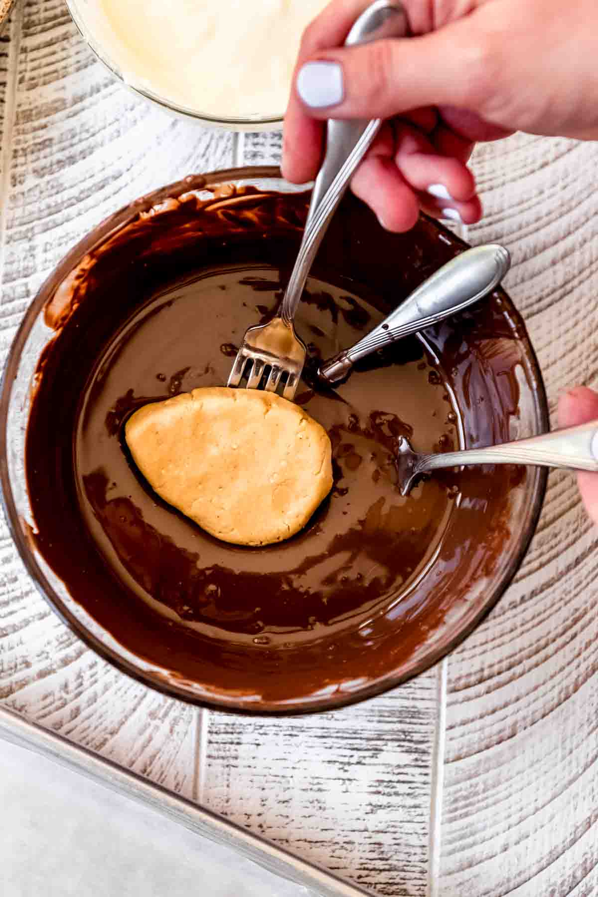 Dipping a peanut butter egg center into melted chocolate.