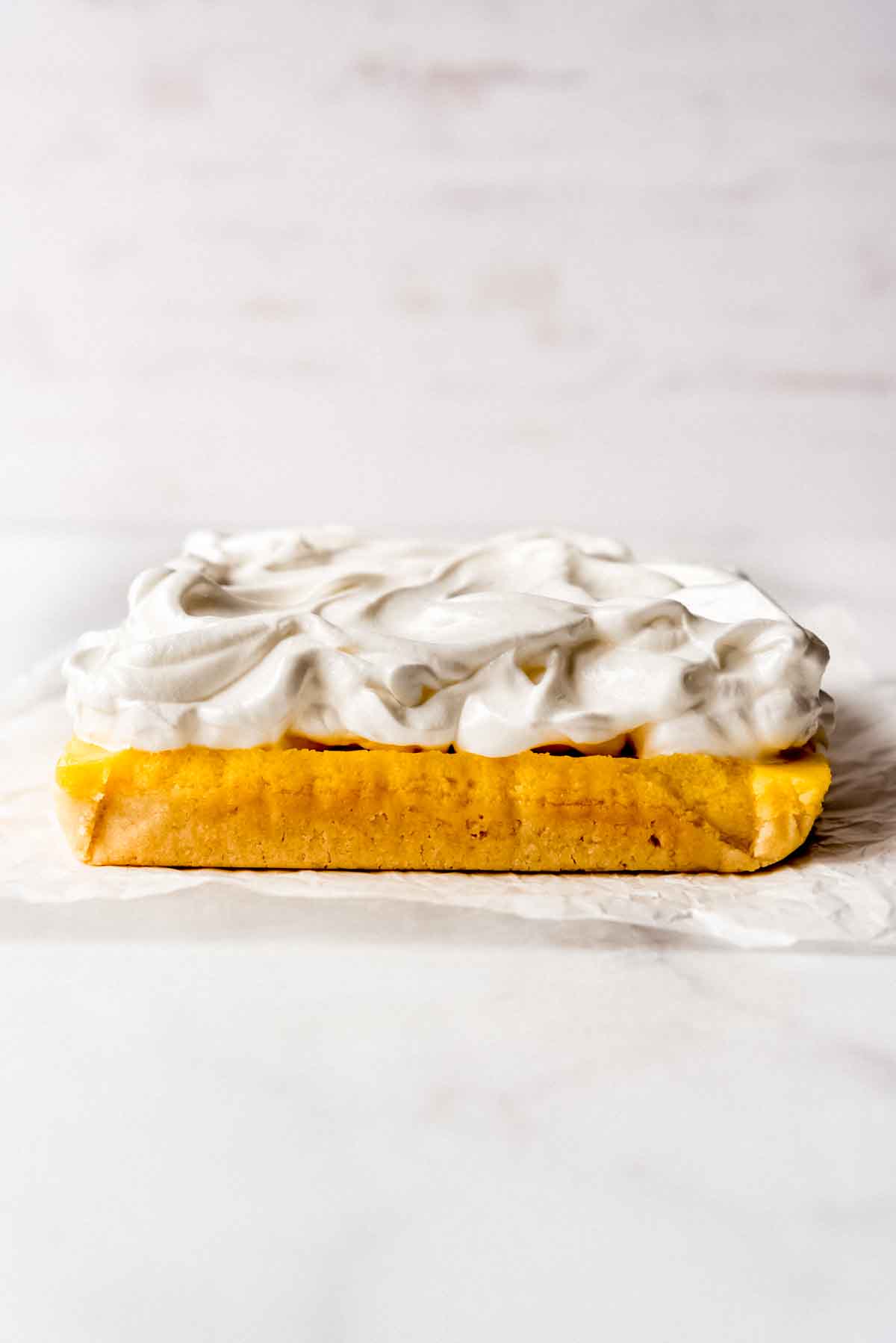 Meringue topping is spread over the lemon pie bar base, prior to toasting. 