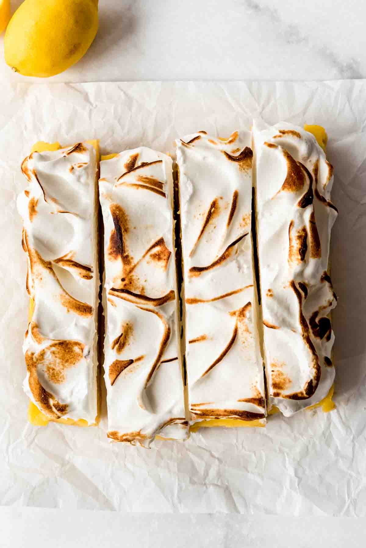 Lemon meringue pie bars being sliced into squares.