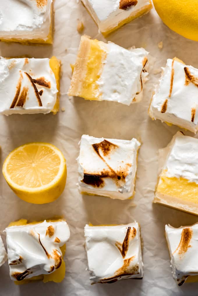 lemon meringue pie bars cut into squares next to a lemon that has been sliced in half