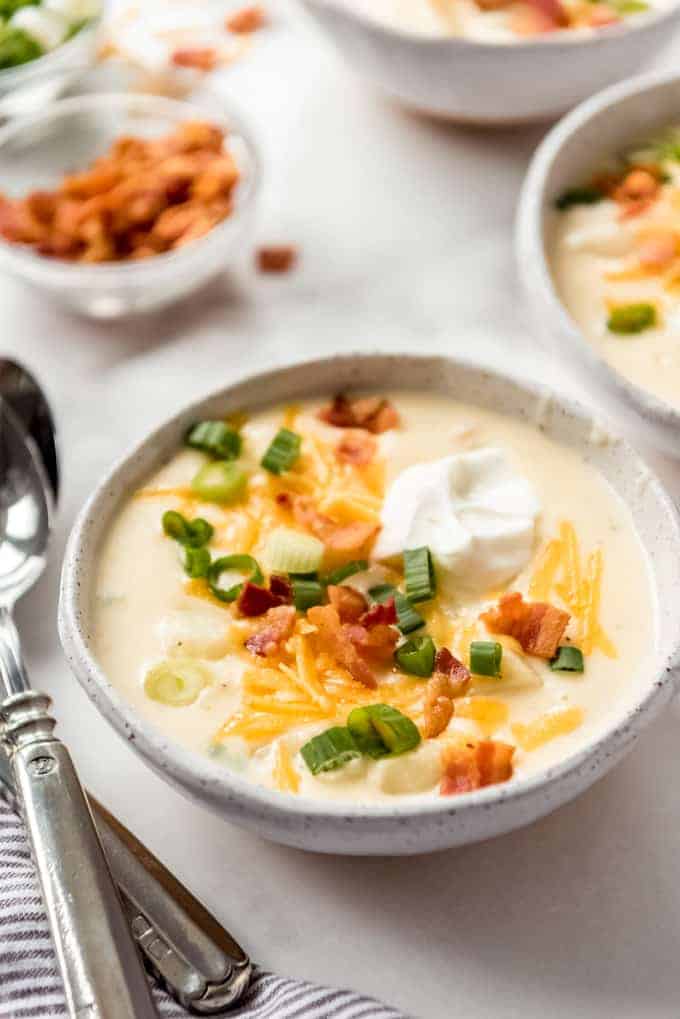 bowl of loaded baked potato soup next to spoons, close up