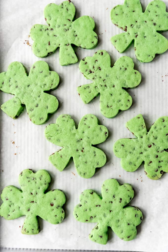 Baked shamrock cookies on a baking sheet lined with parchment paper.