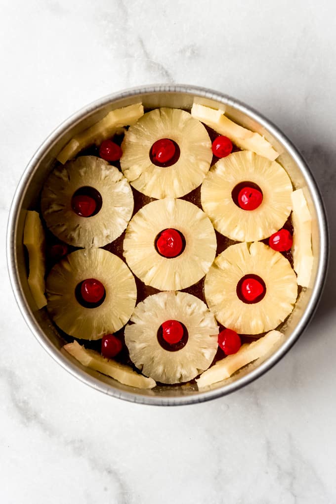 pineapple slices and maraschino cherries arranged decoratively in a cake pan