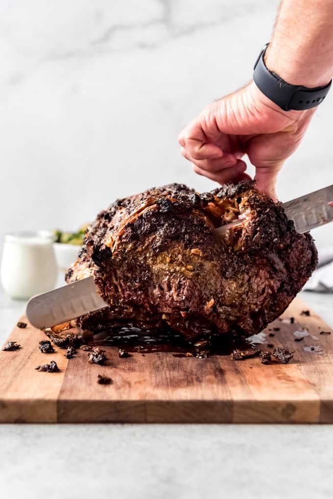 Slicing roasted prime rib on wooden board