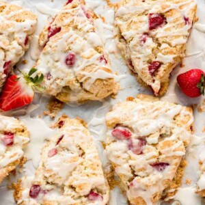 strawberry scones on a baking sheet with glazed drizzled over them
