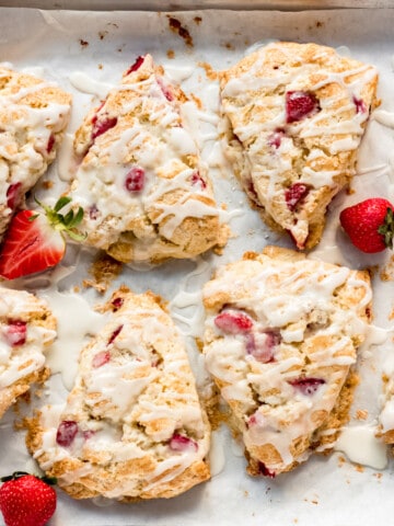 strawberry scones on a baking sheet with glazed drizzled over them