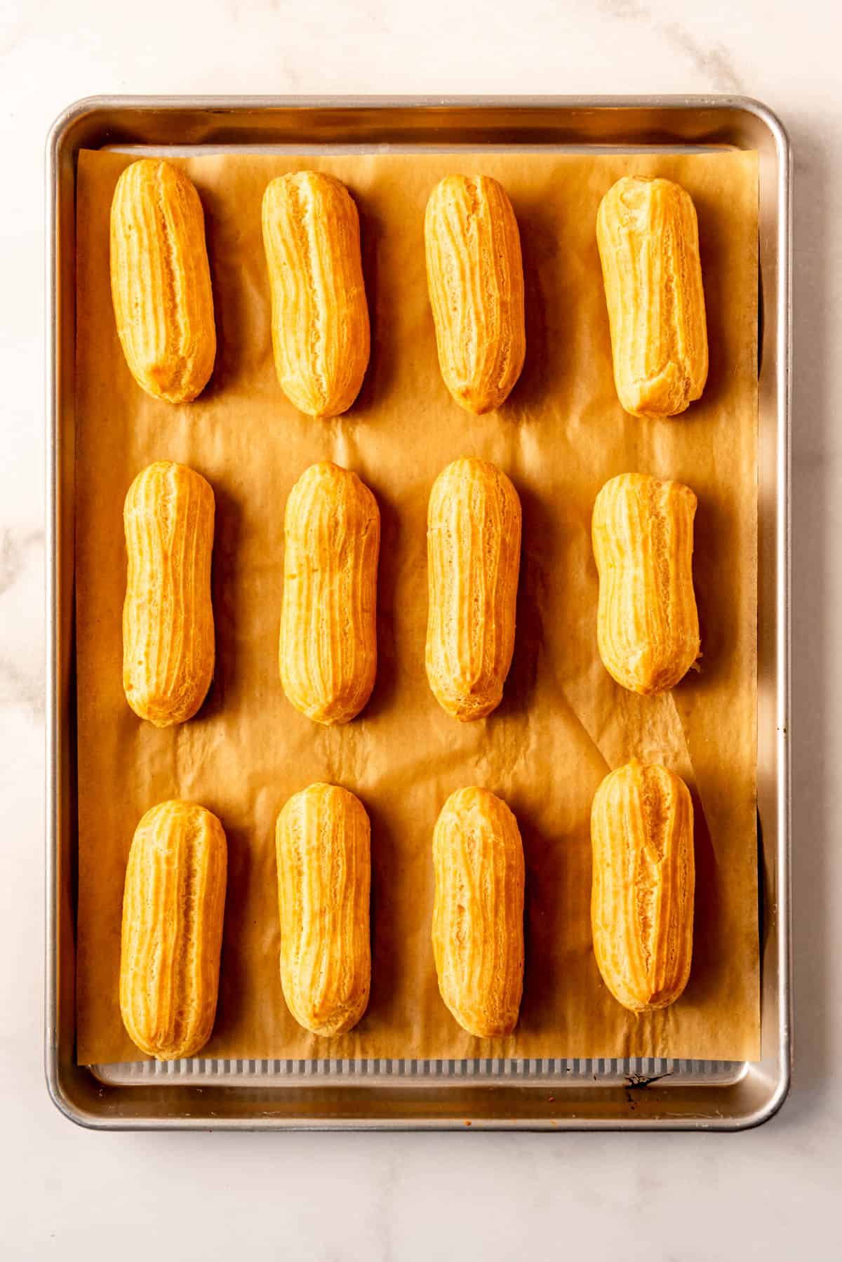 golden brown eclair shells on parchment paper