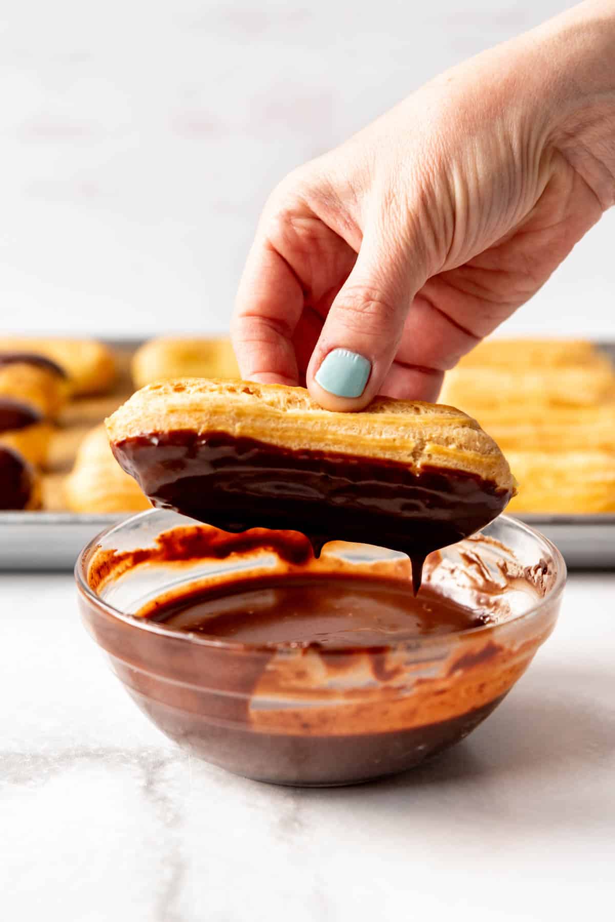 Dipping a chocolate eclair into ganache.