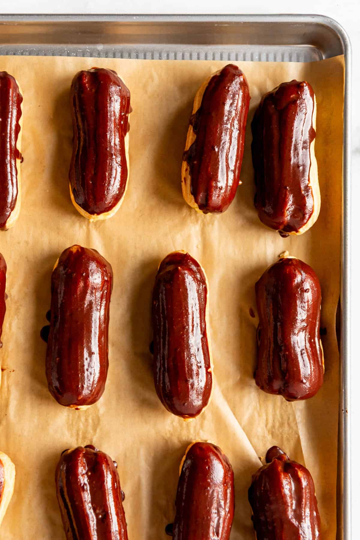 A close image of chocolate eclairs on a baking sheet.