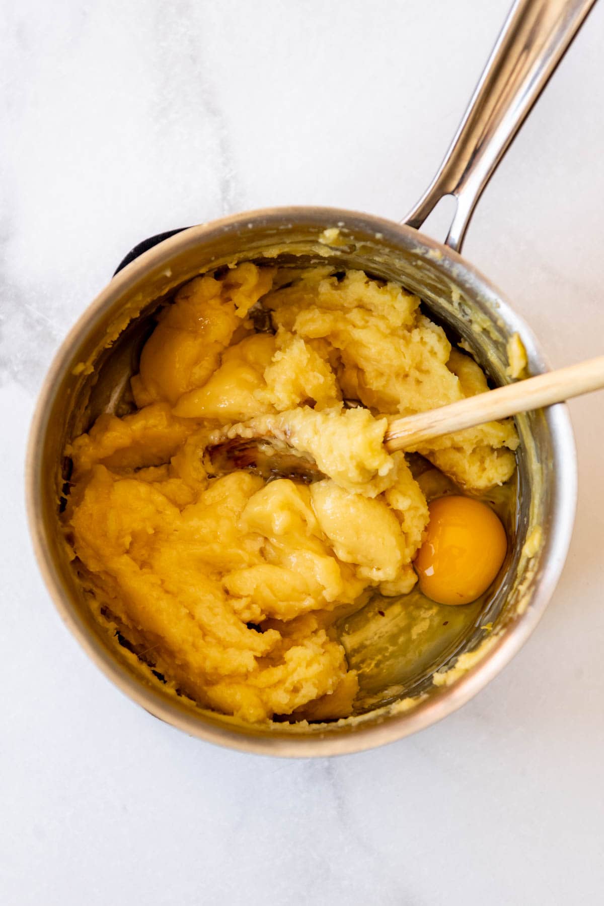 Adding eggs to make choux pastry dough.