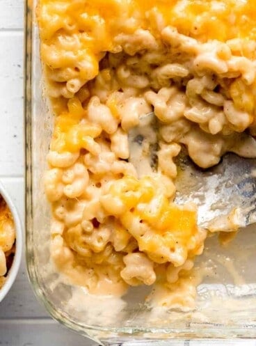 macaroni and cheese being scooped out of a casserole dish