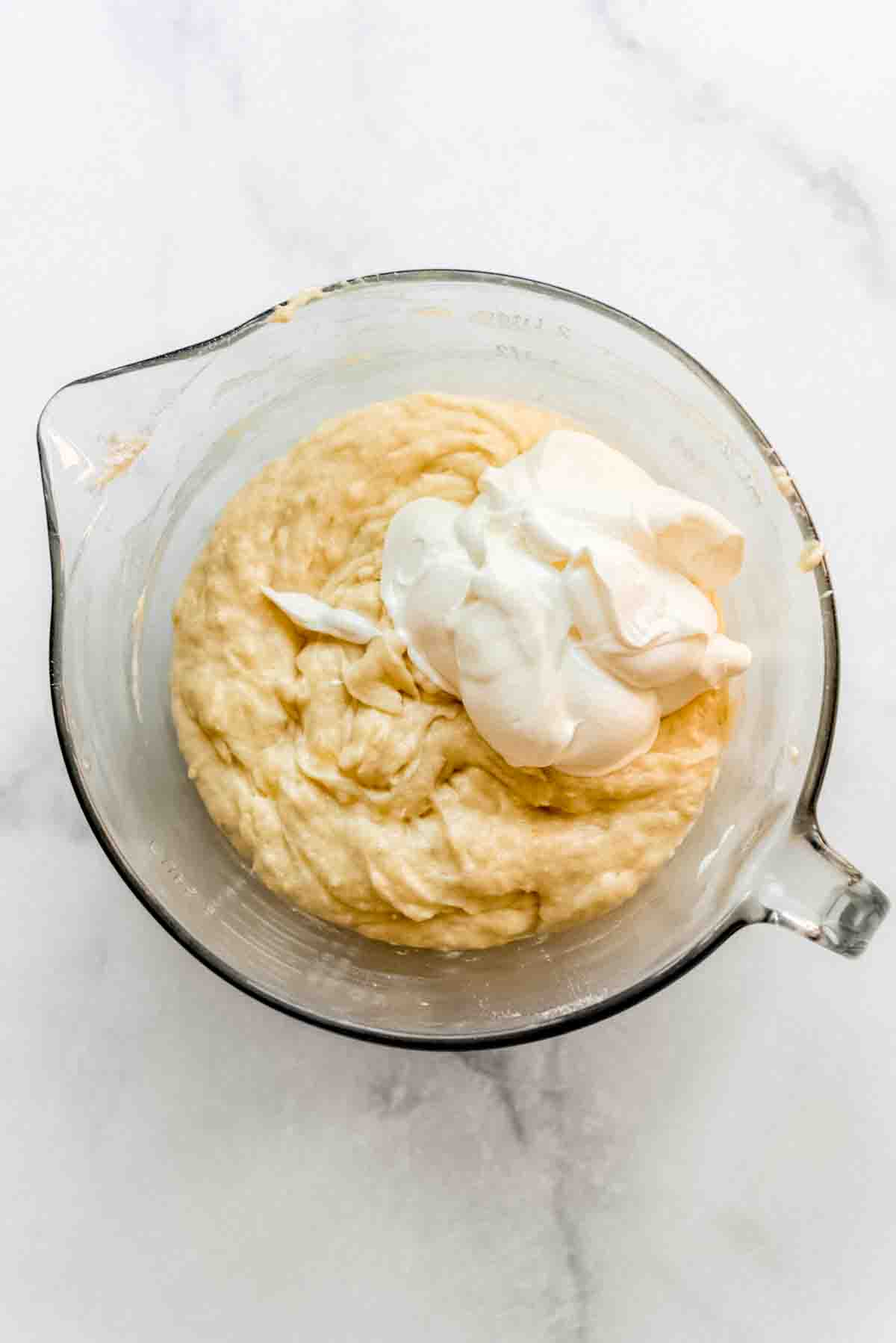 Dollops of sour cream are resting on top of the banana bar mixture, ready to be combined. 