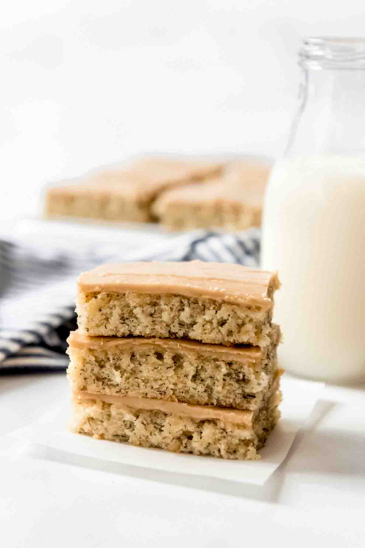 Three banana bars with penuche frosting stacked on top of each other.