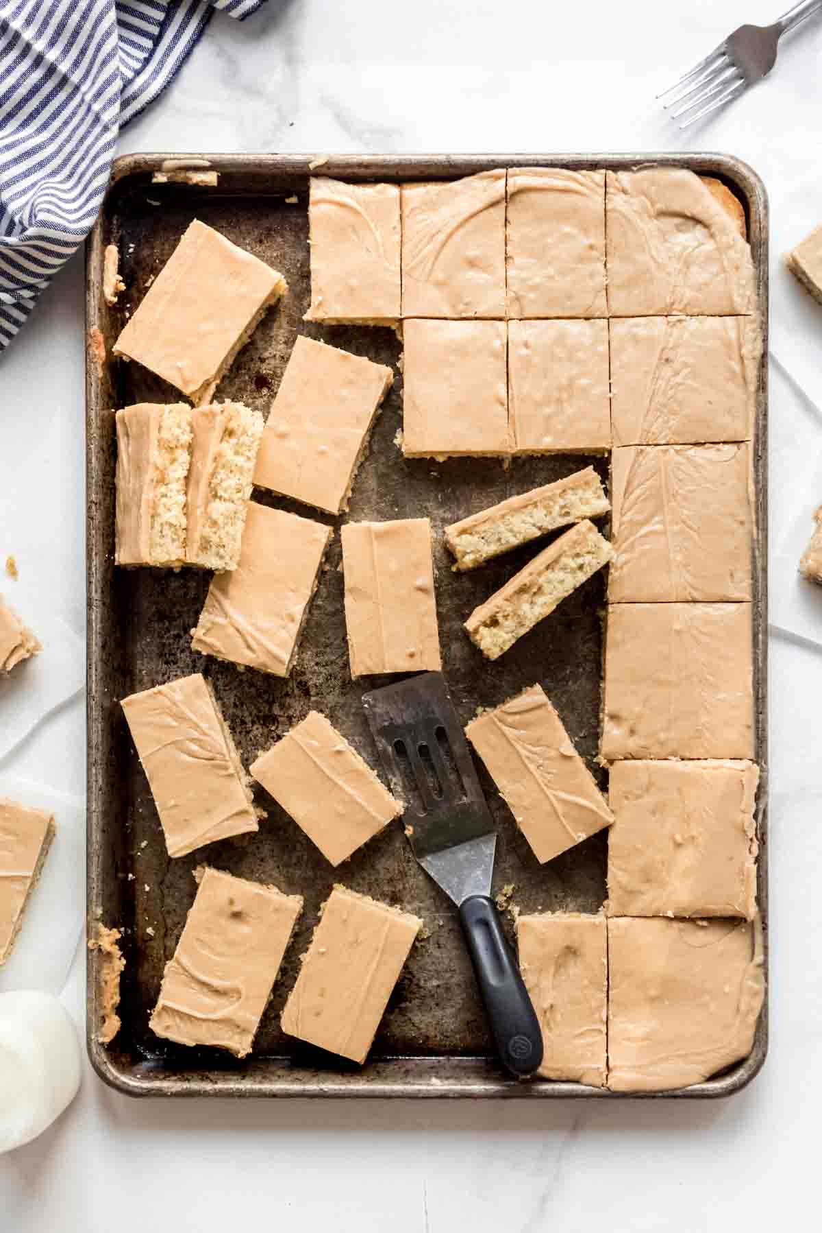 A baking sheet with sliced frosted banana bars.