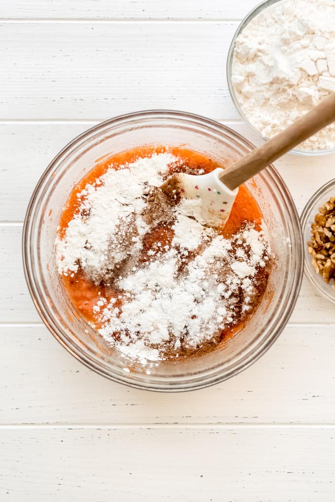 mixing spices and baking powder into carrot bread batter in a bowl