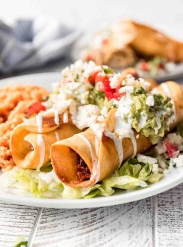 Two chicken flautas on a plate.