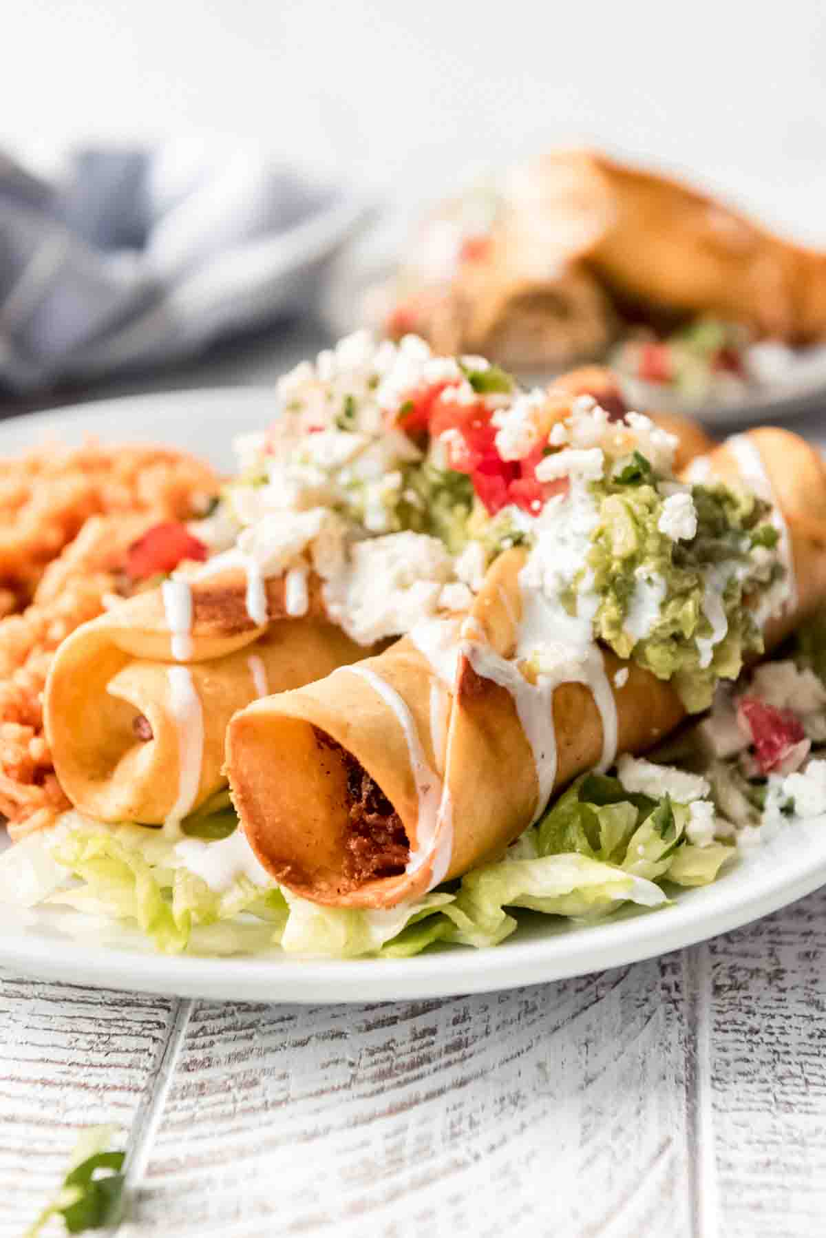 Two chicken flautas on a plate.