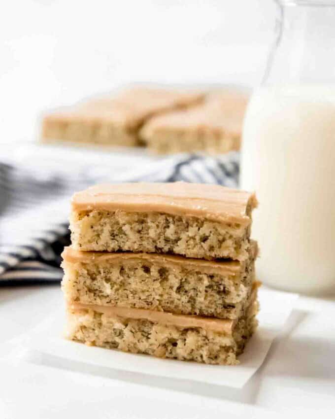 Three banana bars with penuche frosting stacked on top of each other.