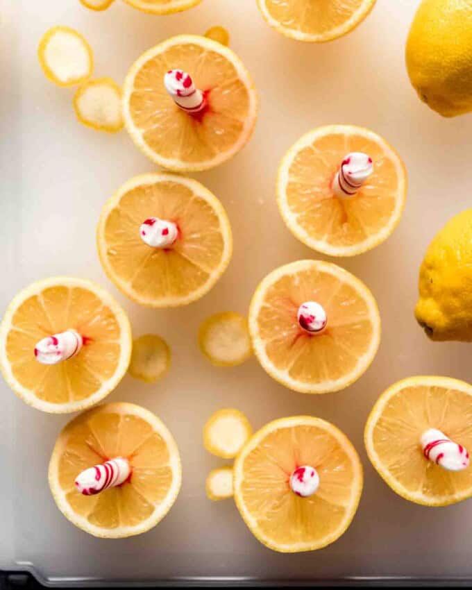 Peppermint sticks stuck into sliced lemon halves.