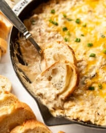 Baguette slices in a skillet of hot crab dip.