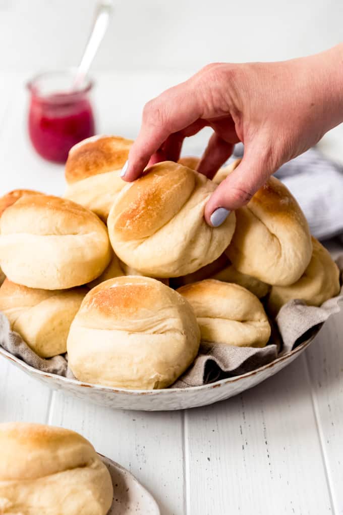 hand grabbing parker house roll out of bread bowl