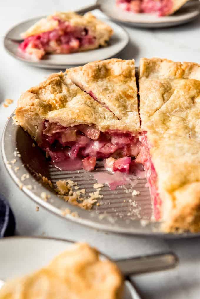 A rhubarb pie sliced into slices with a couple of slices removed and served on plates