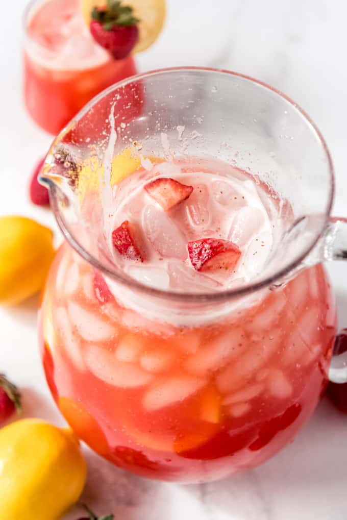 Strawberry lemonade in a pitcher with ice and fresh strawberries