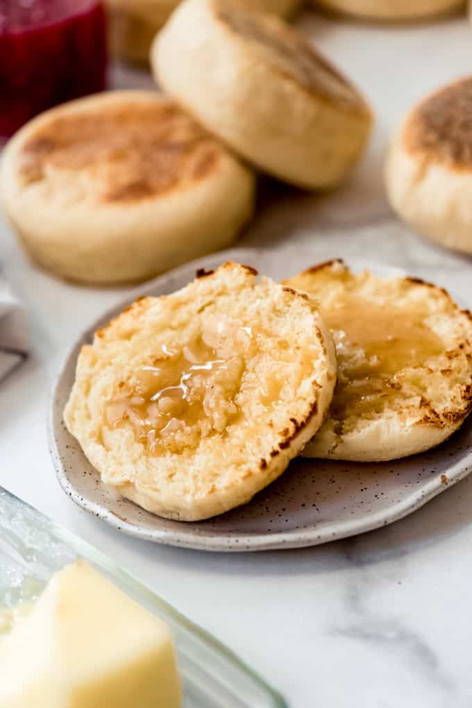 a sliced, toasted english muffin with butter and honey on it