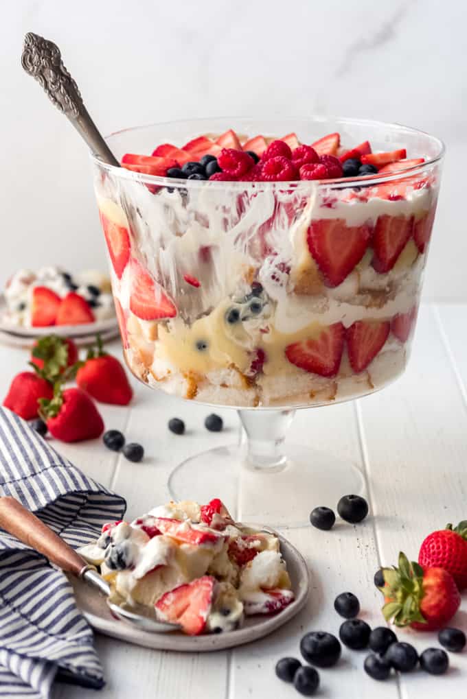 a serving of berry trifle on a plate in front of a trifle dish