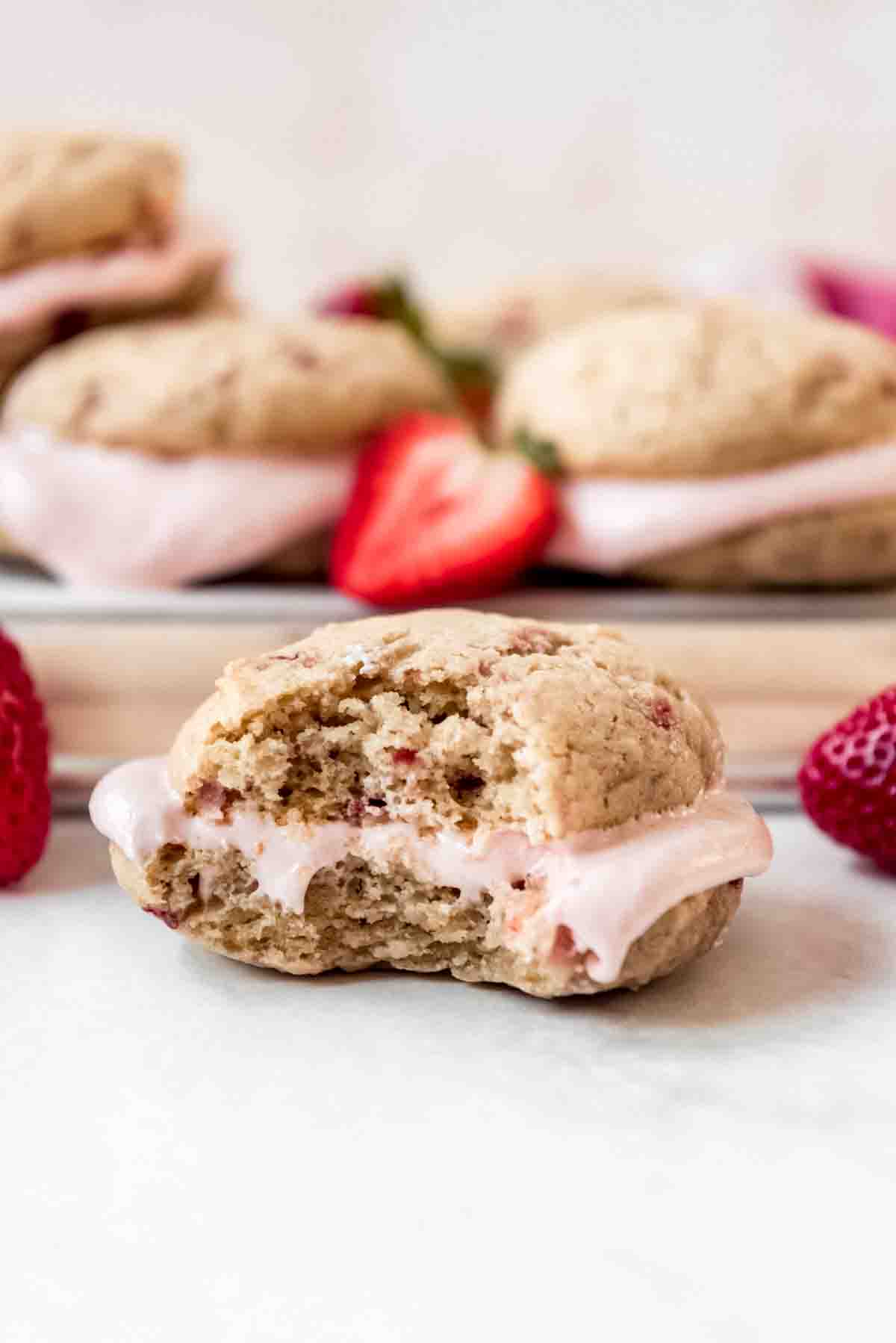 A strawberry whoopie pie with a bite taken out of it.