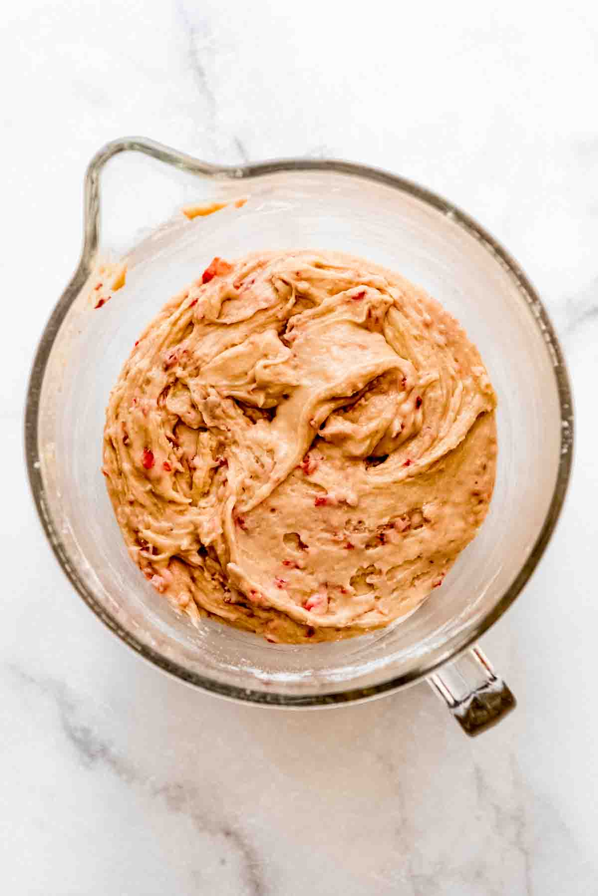 Strawberry whoopie pie batter is blended in a large glass measuring bowl. 