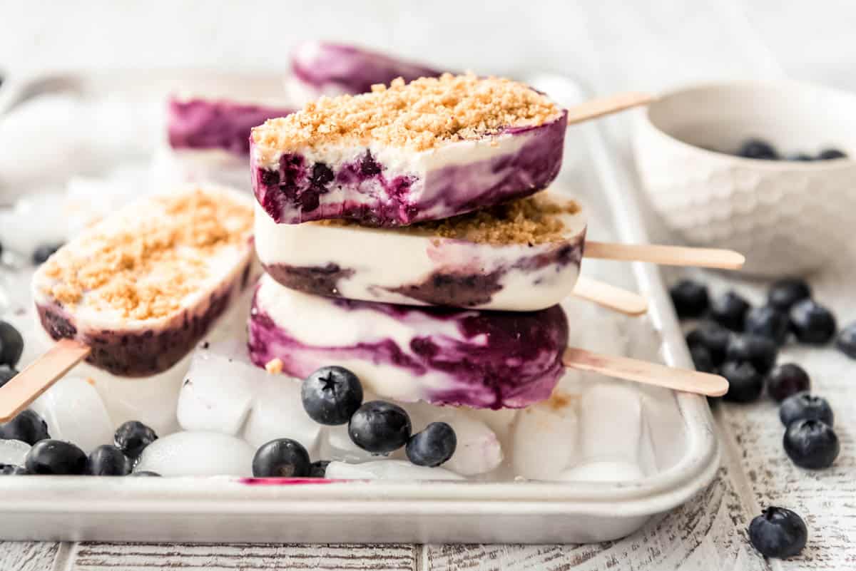 a stack of homemade popsicles with blueberries scattered around them