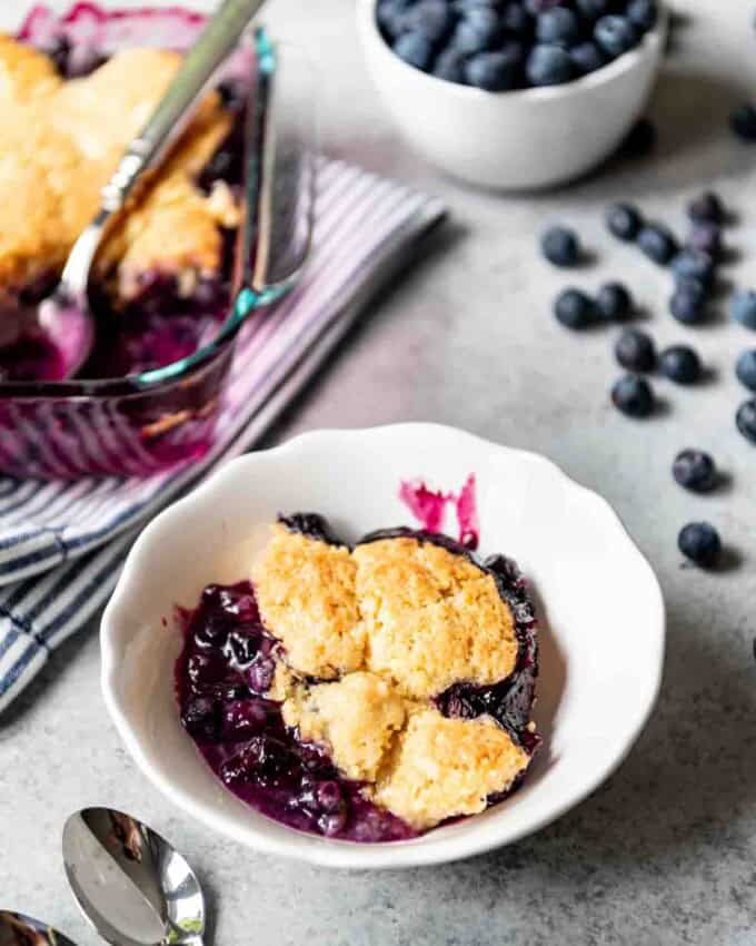 A serving of homemade blueberry cobbler is placed in a white bowl.