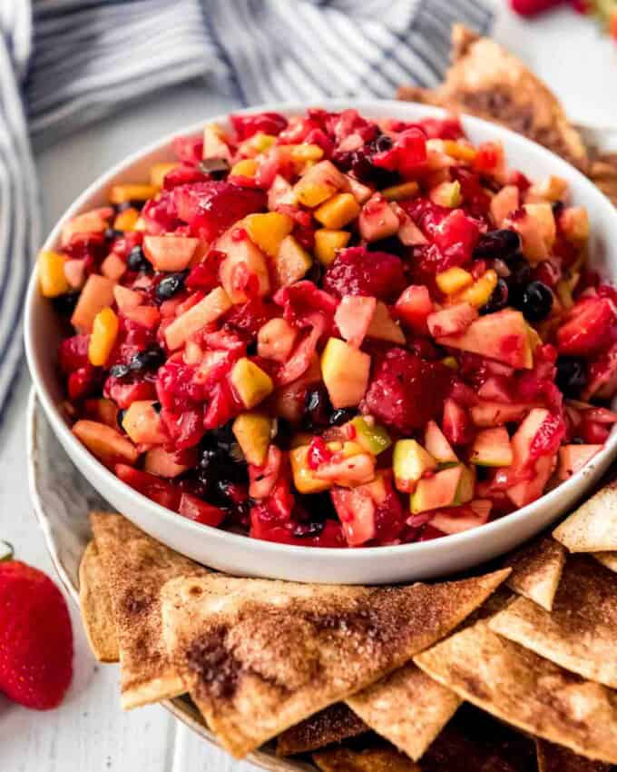 A bowl of fruit salsa with cinnamon chips on the side.