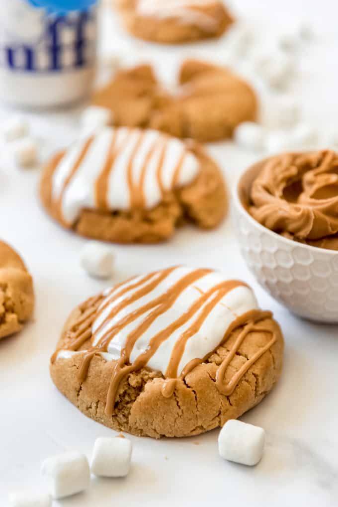 peanut butter cookies topped with marshmallow fluff next to a bowl of peanut butter