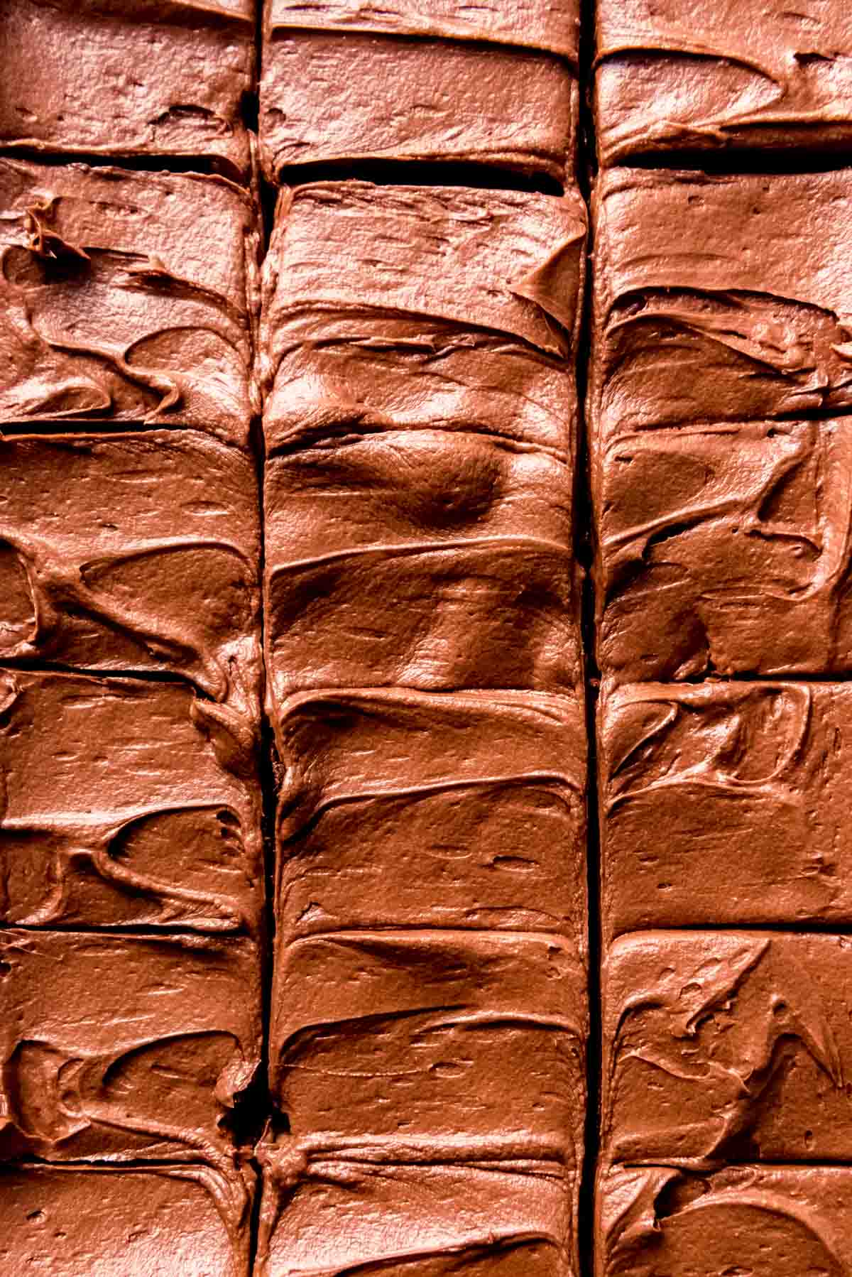 A close image of chocolate frosting on brownies that have been sliced into squares.