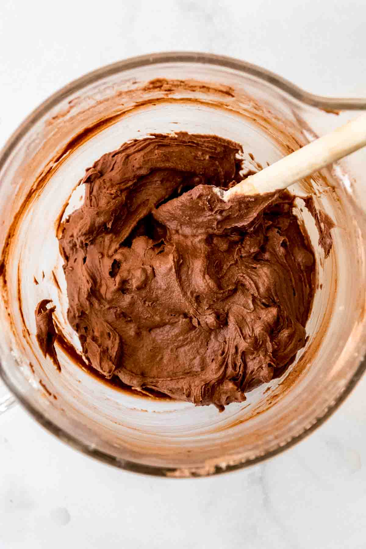 Ingredients have been blended in a glass bowl, creating a brown brownie batter. 